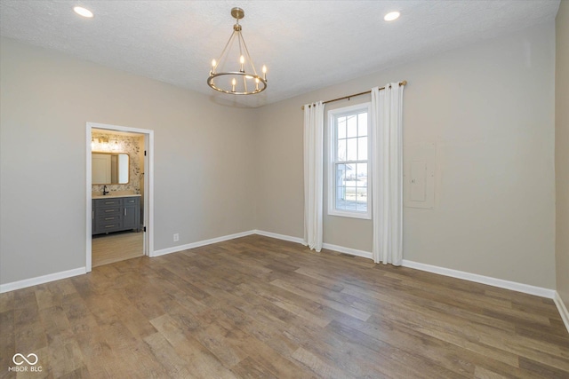 spare room with wood-type flooring, a textured ceiling, and a chandelier