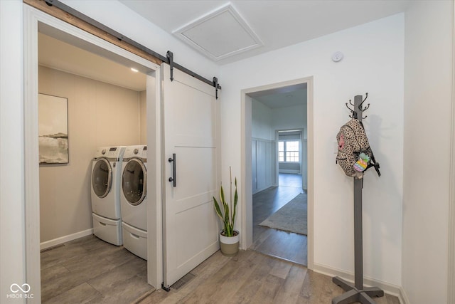 laundry room featuring a barn door, washer and clothes dryer, and light hardwood / wood-style flooring