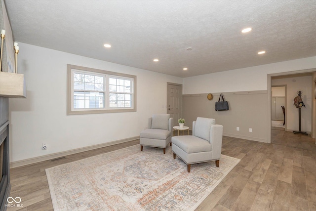 living area featuring a textured ceiling and light hardwood / wood-style floors