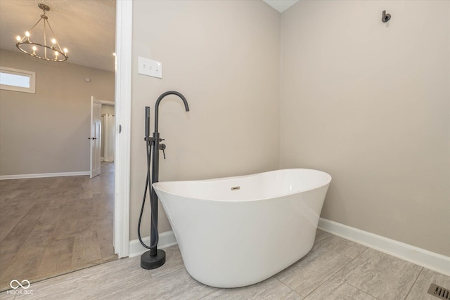 bathroom featuring a tub to relax in, hardwood / wood-style flooring, and a notable chandelier