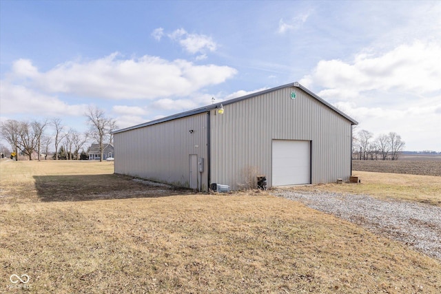 view of outdoor structure with a garage, a yard, and a rural view