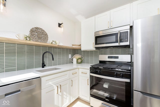 kitchen with backsplash, appliances with stainless steel finishes, sink, and white cabinets