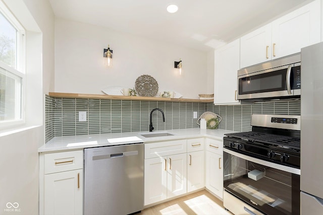 kitchen featuring white cabinetry, sink, backsplash, and appliances with stainless steel finishes