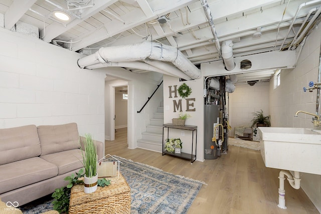 basement with sink, gas water heater, and light hardwood / wood-style floors