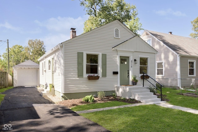 bungalow featuring a garage, an outdoor structure, and a front lawn