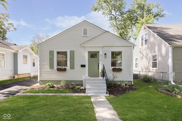 bungalow-style home with cooling unit and a front lawn