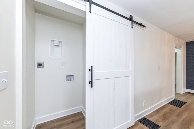 interior space featuring hardwood / wood-style floors, hookup for a washing machine, a barn door, and hookup for an electric dryer