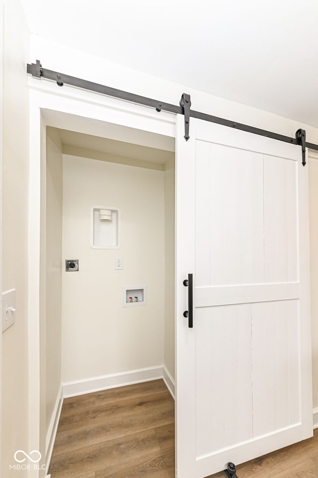 laundry room featuring hookup for a washing machine, wood-type flooring, a barn door, and hookup for an electric dryer