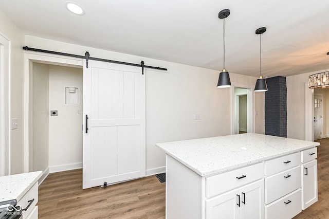 kitchen featuring white cabinetry, a barn door, a center island, and hanging light fixtures