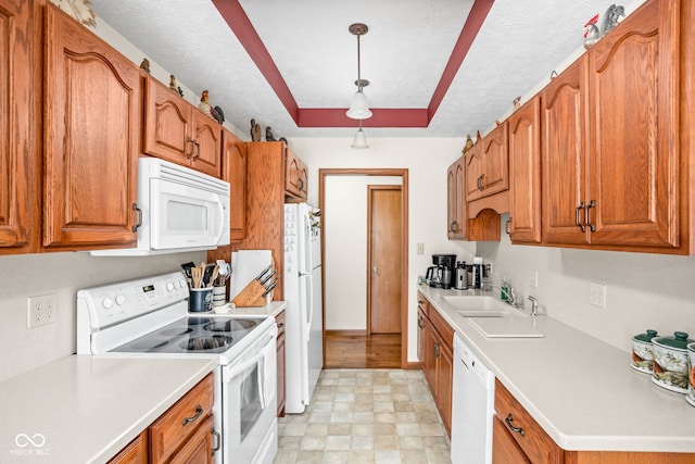 kitchen with white appliances, a raised ceiling, sink, and a textured ceiling