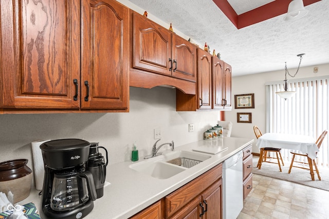 kitchen featuring pendant lighting, sink, a textured ceiling, and dishwasher