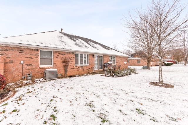 snow covered rear of property featuring central air condition unit