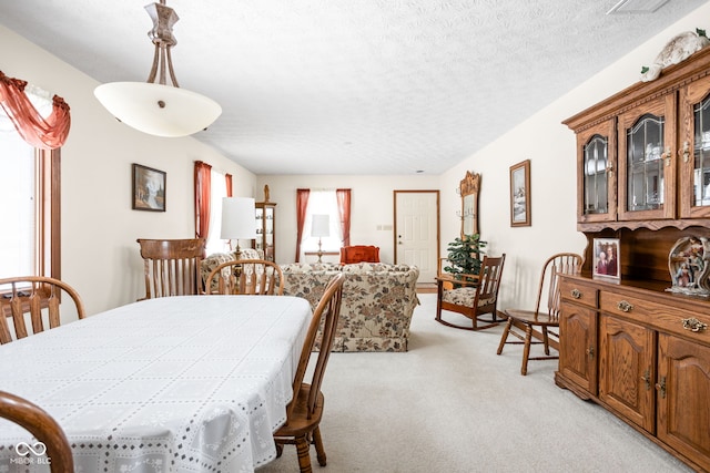 dining area featuring light carpet and a textured ceiling