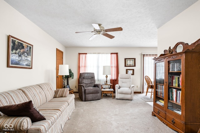 living room with a textured ceiling, light colored carpet, and ceiling fan