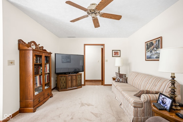 living room featuring light carpet, a textured ceiling, and ceiling fan