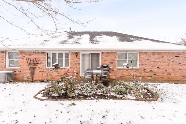 snow covered back of property with central AC