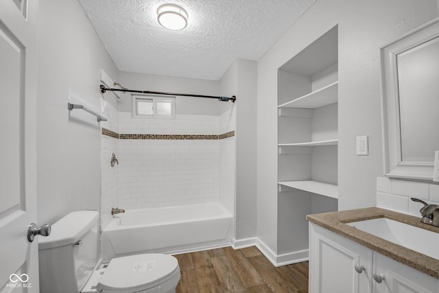 full bathroom with tiled shower / bath combo, vanity, wood-type flooring, a textured ceiling, and toilet