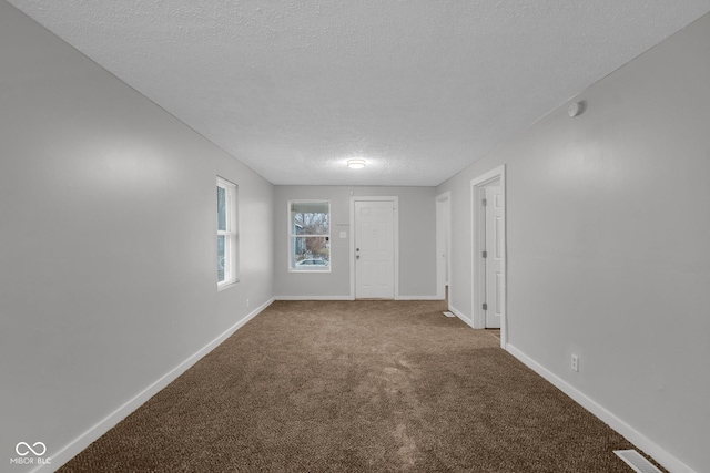 carpeted empty room featuring a textured ceiling