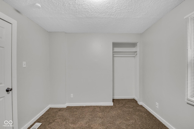 unfurnished bedroom with carpet floors, a textured ceiling, and a closet