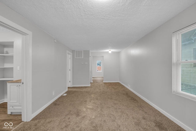 carpeted spare room with a textured ceiling