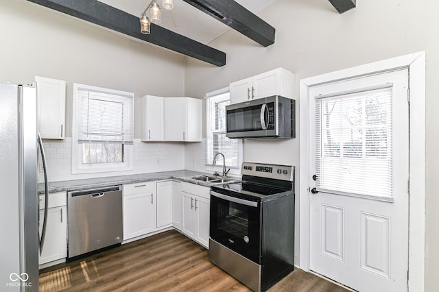 kitchen featuring appliances with stainless steel finishes, dark wood-type flooring, white cabinetry, a sink, and beamed ceiling