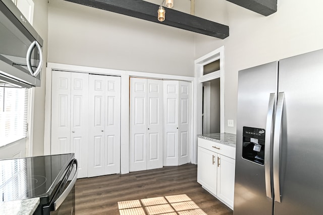 kitchen featuring appliances with stainless steel finishes, white cabinets, dark wood-type flooring, and light stone counters
