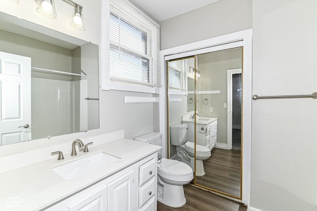 bathroom featuring toilet, baseboards, wood finished floors, and vanity