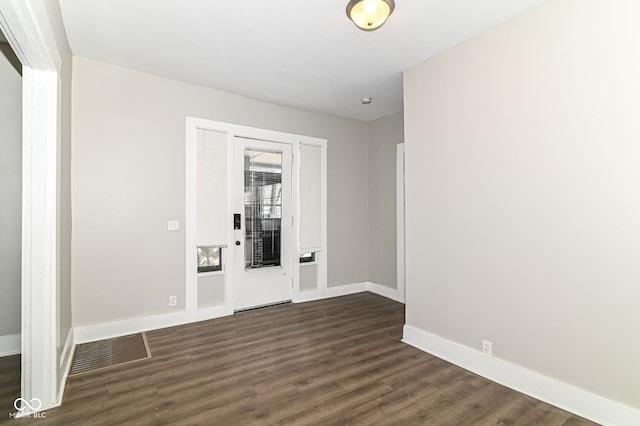 spare room featuring baseboards, visible vents, and dark wood-type flooring