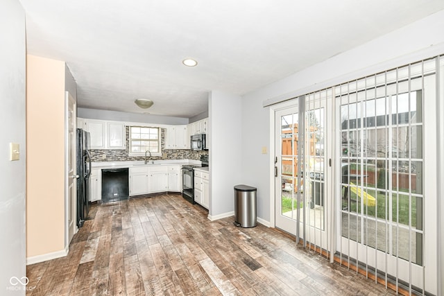 kitchen featuring sink, hardwood / wood-style flooring, white cabinetry, black appliances, and decorative backsplash