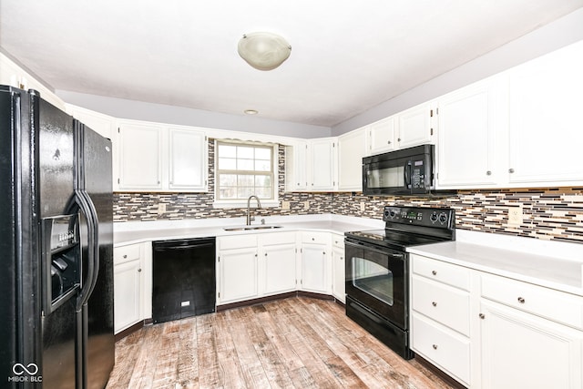 kitchen with sink, black appliances, light hardwood / wood-style flooring, white cabinets, and backsplash