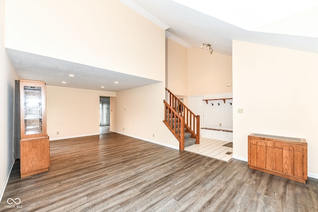 unfurnished room with wood-type flooring and high vaulted ceiling