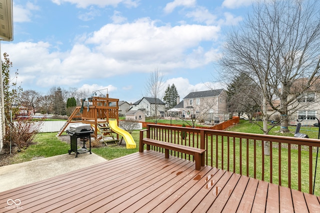 wooden terrace featuring a grill, a playground, a patio area, and a lawn