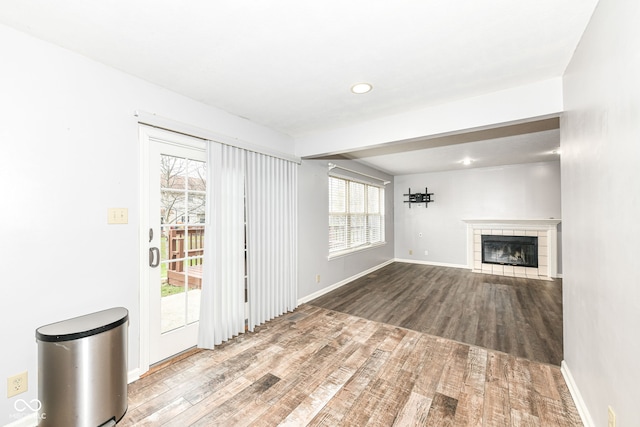 unfurnished living room featuring hardwood / wood-style floors and a tile fireplace