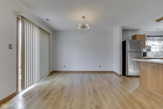 unfurnished living room featuring sink, light hardwood / wood-style floors, and a textured ceiling