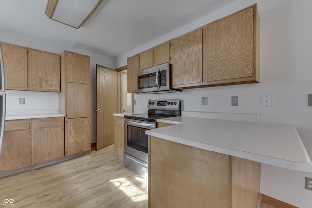 kitchen with appliances with stainless steel finishes, light brown cabinets, and light wood-type flooring