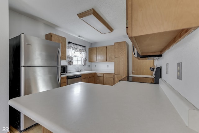 kitchen featuring sink, kitchen peninsula, and appliances with stainless steel finishes