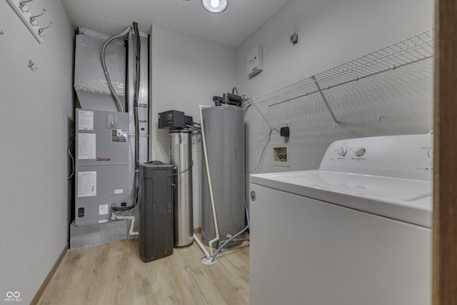 clothes washing area with washer / dryer, light hardwood / wood-style floors, and heating unit