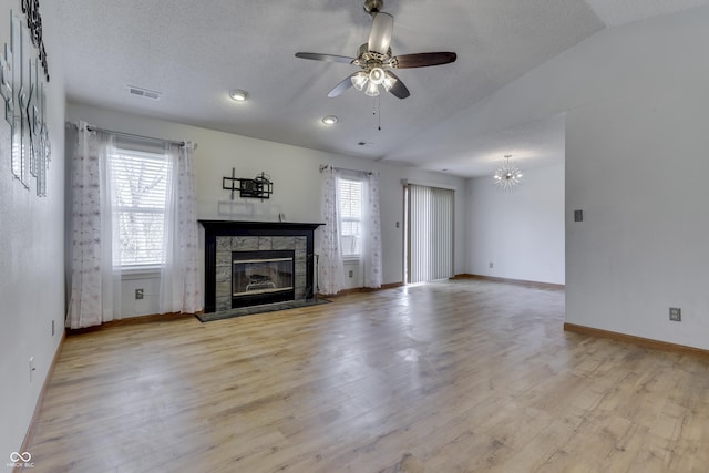 unfurnished living room featuring lofted ceiling, a healthy amount of sunlight, a fireplace, and light wood-type flooring