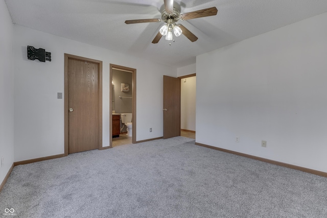 unfurnished bedroom with light carpet, a textured ceiling, ceiling fan, and ensuite bathroom