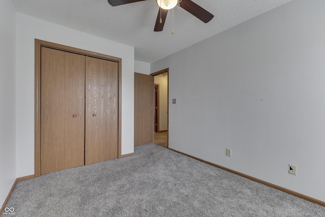 unfurnished bedroom with ceiling fan, light colored carpet, a closet, and a textured ceiling