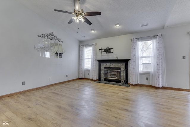 unfurnished living room with a textured ceiling, a fireplace, a healthy amount of sunlight, and light wood-type flooring