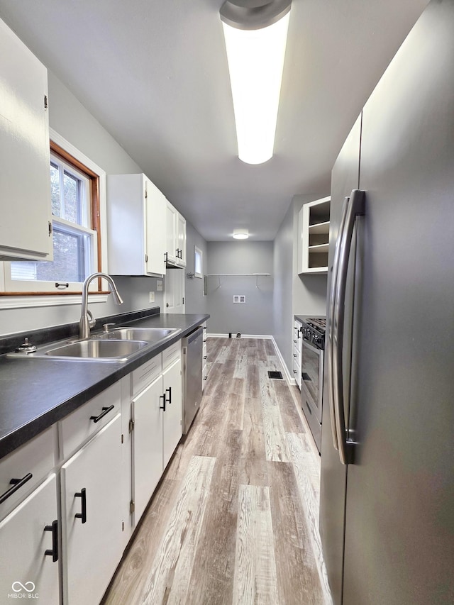 kitchen with white cabinetry, stainless steel appliances, sink, and light wood-type flooring