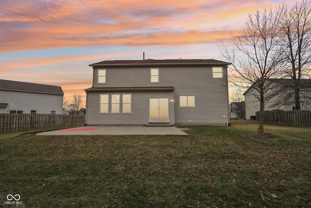 back house at dusk featuring a patio and a yard