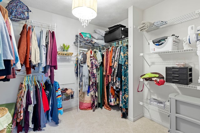 walk in closet with light carpet and a chandelier