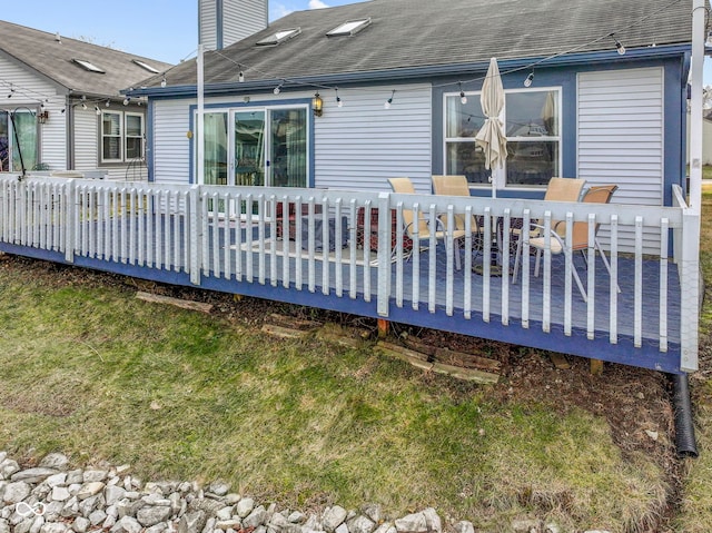 rear view of property featuring a wooden deck and a lawn