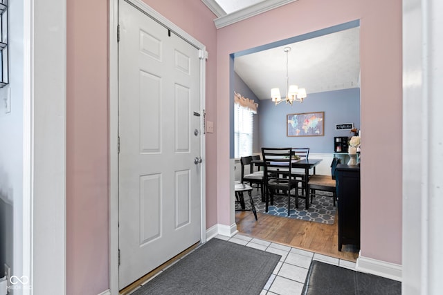 tiled foyer entrance featuring vaulted ceiling and a chandelier