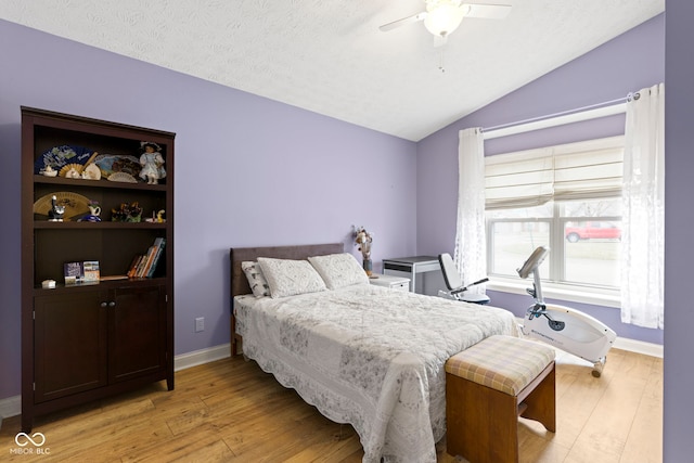 bedroom featuring vaulted ceiling, a textured ceiling, ceiling fan, and light hardwood / wood-style floors