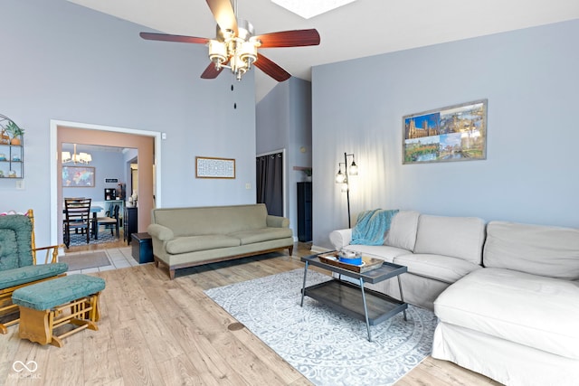 living room featuring high vaulted ceiling, ceiling fan with notable chandelier, and light hardwood / wood-style floors