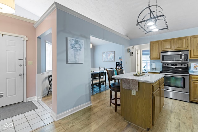 kitchen featuring pendant lighting, stainless steel appliances, a kitchen island, and light hardwood / wood-style flooring