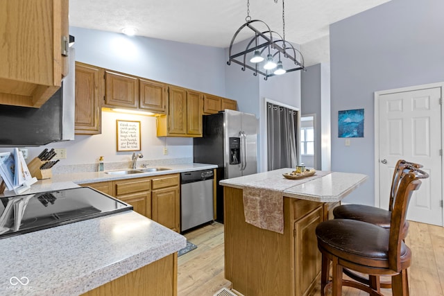 kitchen with vaulted ceiling, a kitchen island, sink, light hardwood / wood-style floors, and stainless steel appliances